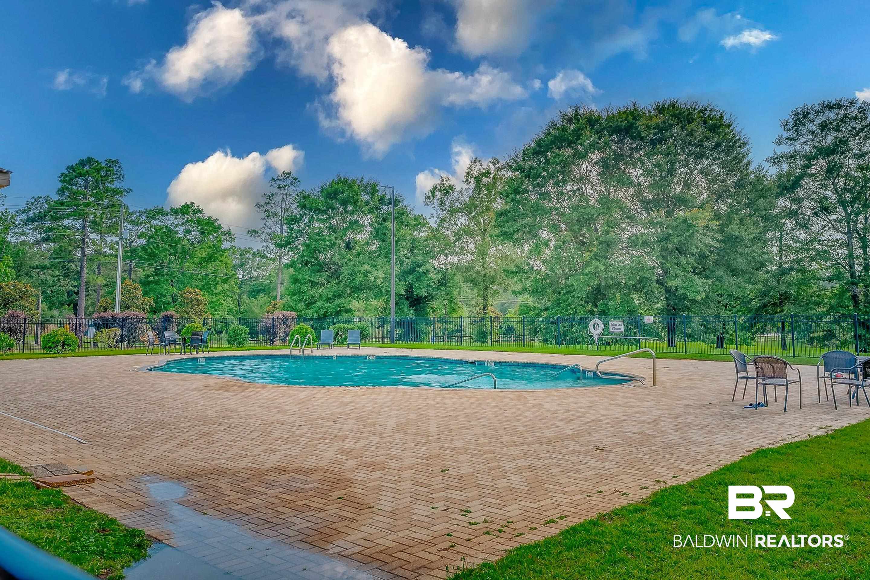 2215 Fernwood Loop West Semmes, AL 36575 - Photo 38 of 40 Curved swimming pool featuring a perimeter fence, surrounding mature trees, and a spacious paver patio