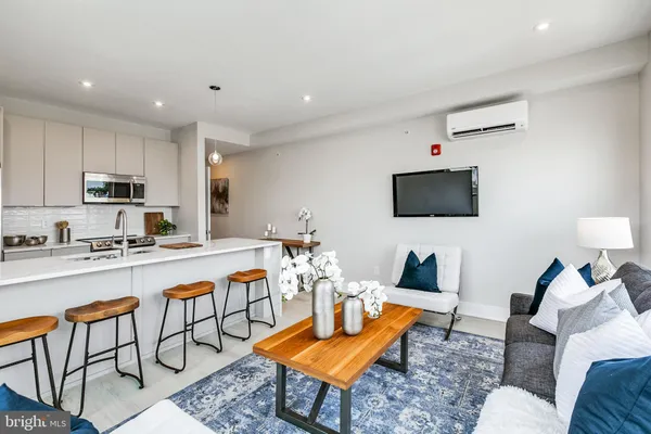 a living room with furniture a flat screen tv and kitchen view