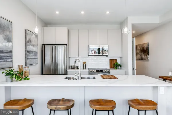 a kitchen with stainless steel appliances a dining table and chairs in it