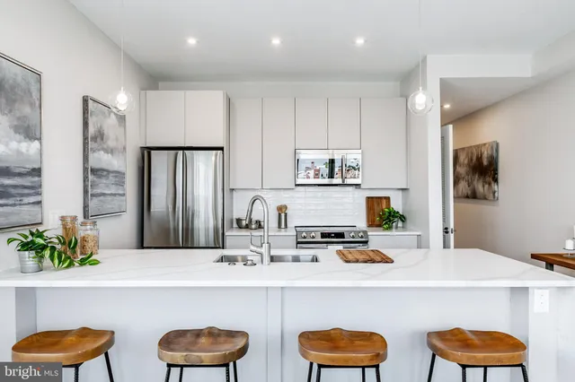 a kitchen with stainless steel appliances a dining table and chairs in it