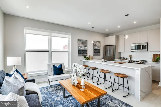 a living room with stainless steel appliances furniture a rug and a window