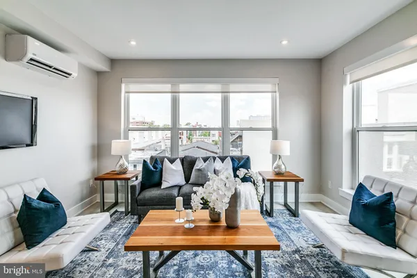 a living room with furniture a table and large windows