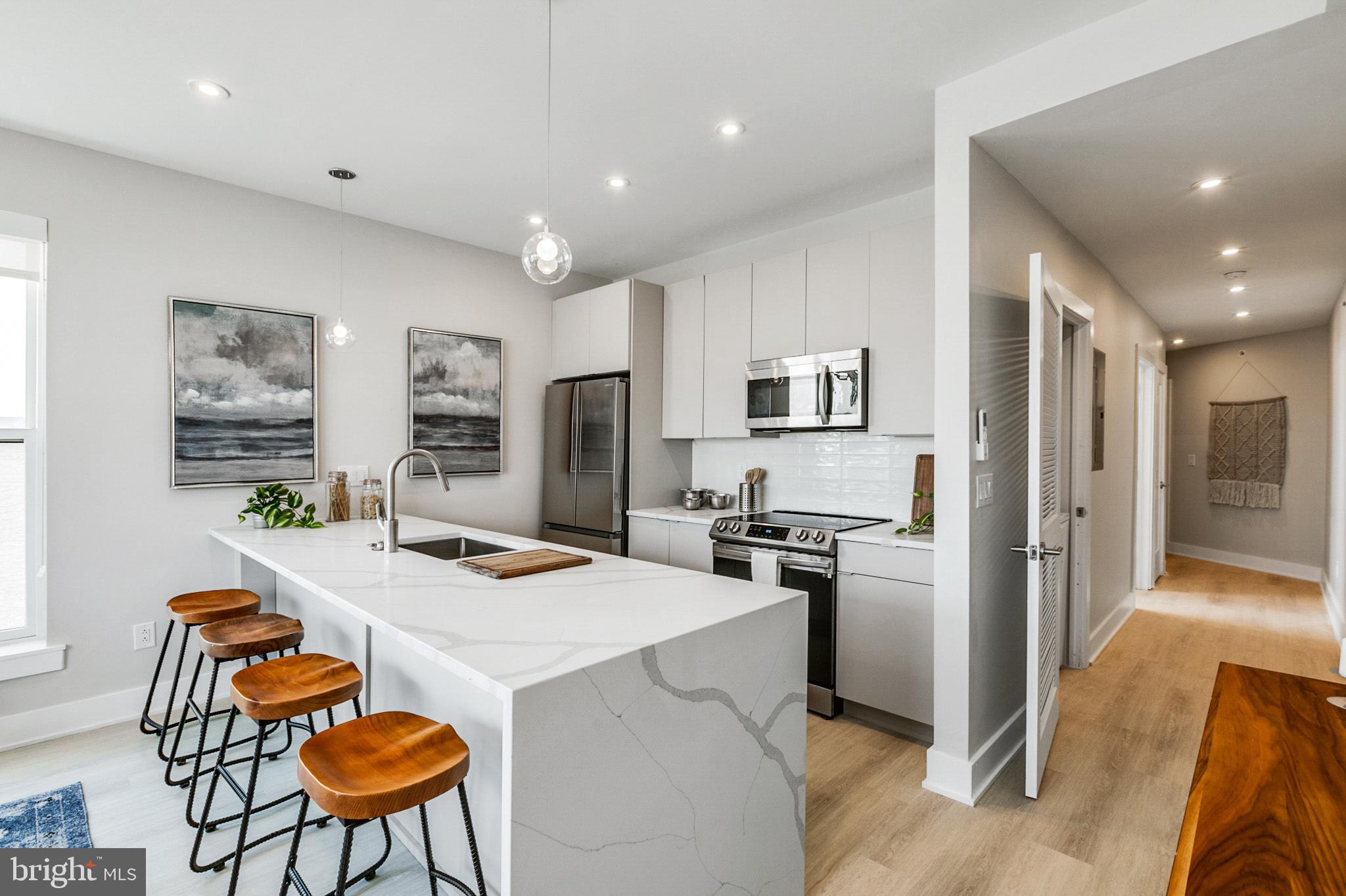 1533 Ridge Avenue, Unit 506 Philadelphia, PA 19130 - Photo 4 of 20 a kitchen with stainless steel appliances kitchen island granite countertop a refrigerator a stove a sink a dining table and chairs with wooden floor