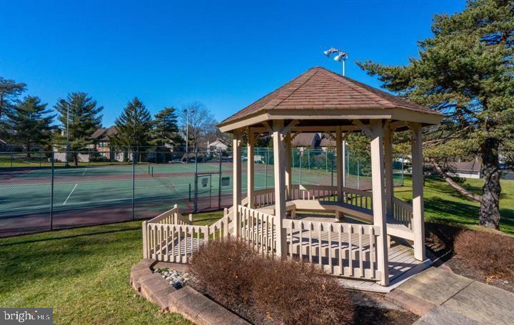 202 Hackberry Court Warrington, PA 18976 - Photo 2 of 7 a view of a deck with a table and chairs under an umbrella with large trees