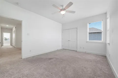 an empty room with chandelier fan and windows