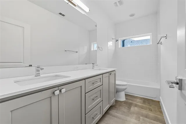 a bathroom with a double vanity sink a toilet and a tub