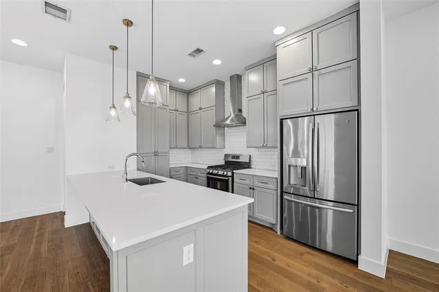 a kitchen with stainless steel appliances a refrigerator sink and wooden floor