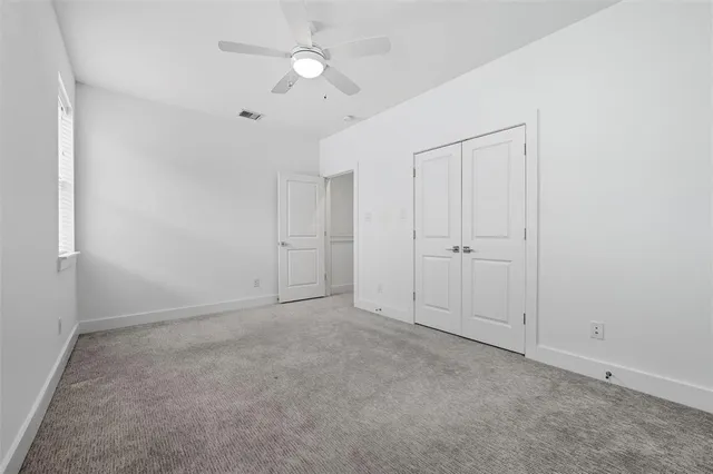 an empty room with a ceiling fan and a window