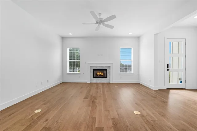 an empty room with wooden floor a ceiling fan and windows