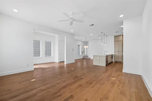 a view of an empty room with wooden floor and a kitchen