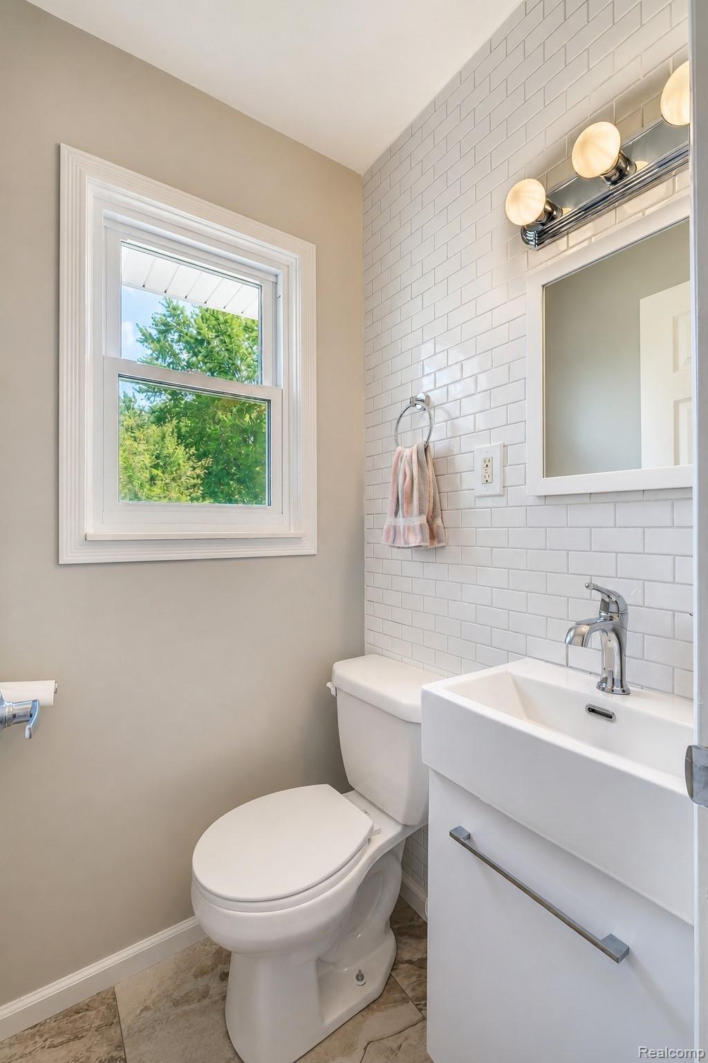 11399 Markley Road Gaines, MI 48436 - Photo 11 of 19 Powder room featuring a subway tile accent wall, contemporary vanity with integrated sink, chrome faucet, and decorative lighting fixture