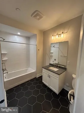 a bathroom with a granite countertop sink a toilet and shower