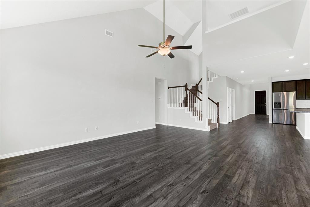7640 Rhyner Way Fort Worth, TX 76137 - Photo 18 of 40 Vaulted ceilings, wood-finish flooring, staircase with white spindles, dark wood cabinetry, and stainless steel refrigerator