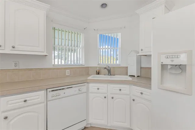 a kitchen with white cabinets and window