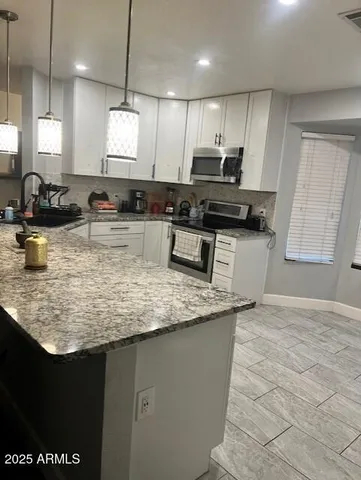 a kitchen with kitchen island granite countertop a sink cabinets and wooden floor