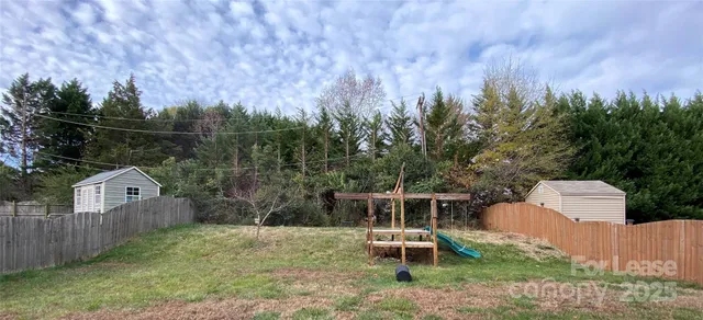 a view of a wooden house with a yard and fence