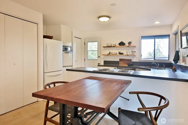 a kitchen with stainless steel appliances granite countertop a stove a refrigerator a sink a dining table and chairs