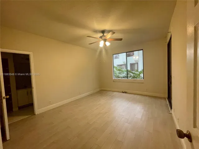 an empty room with windows and fan