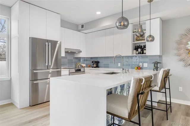 a kitchen with stainless steel appliances granite countertop a sink a stove a refrigerator and island with wooden floor