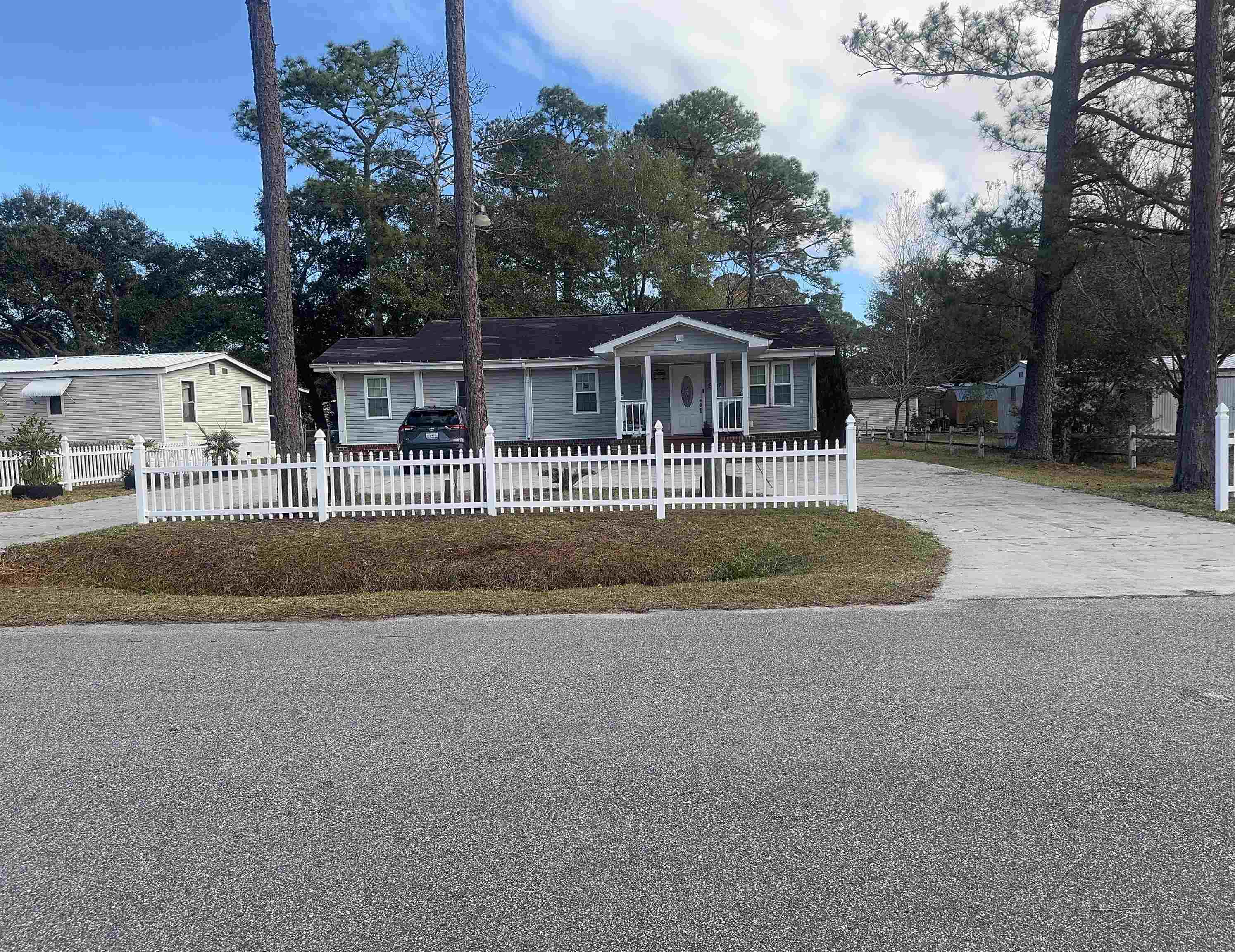View of front of property with a fenced front yard, concrete driveway, and covered porch