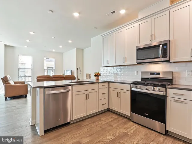 a kitchen with stainless steel appliances granite countertop a stove a sink and a microwave