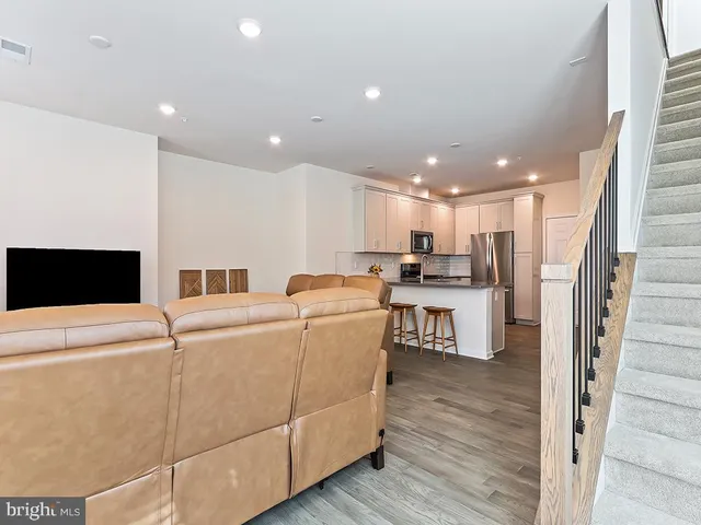 a living room with couches and kitchen view with wooden floor