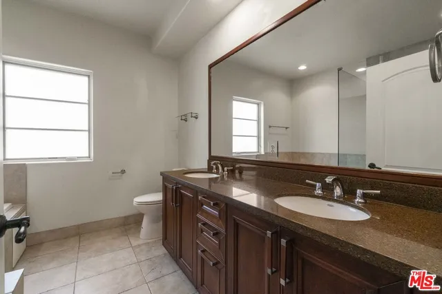 a bathroom with a granite countertop sink a mirror and a toilet