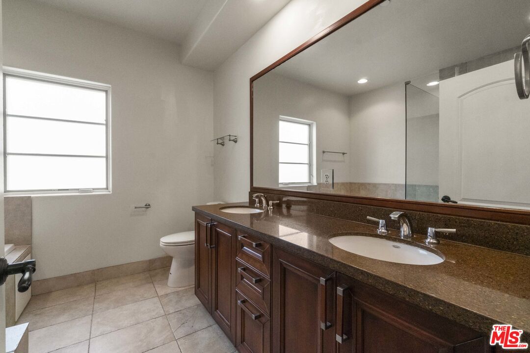 10765 Wilkins Avenue, Unit 8 Los Angeles, CA 90024 - Photo 15 of 33 a bathroom with a granite countertop sink a mirror and a toilet