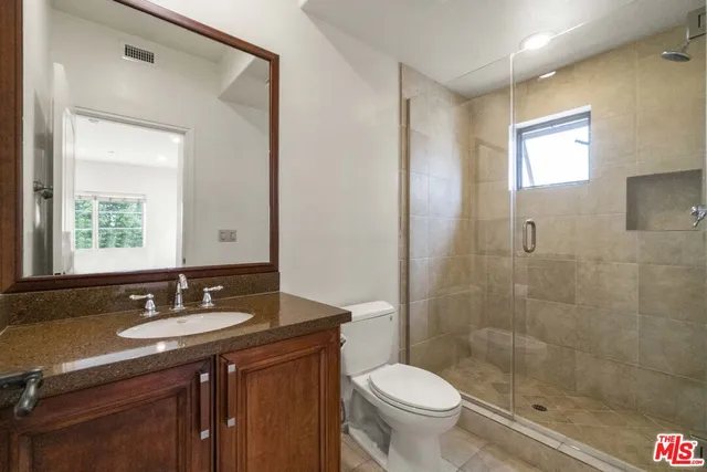 a bathroom with a sink a toilet a mirror and a shower