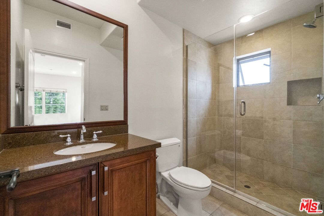 10765 Wilkins Avenue, Unit 8 Los Angeles, CA 90024 - Photo 20 of 33 a bathroom with a sink a toilet a mirror and a shower
