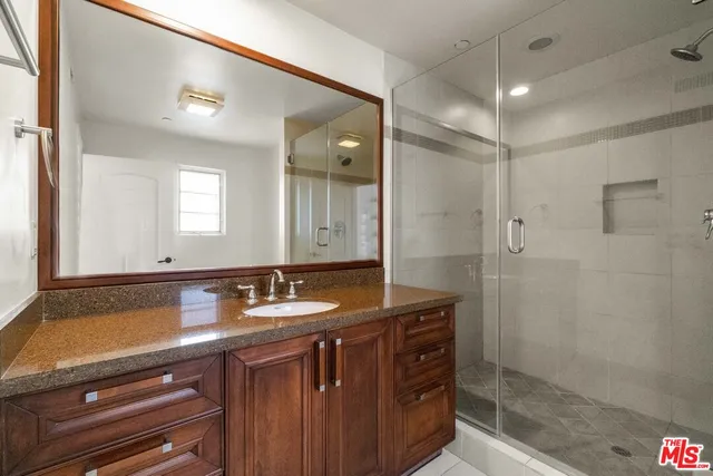 a bathroom with a granite countertop sink a mirror and shower