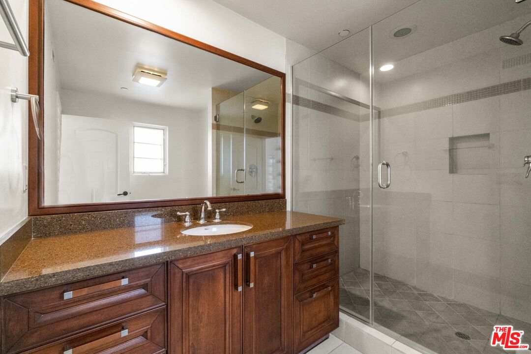 10765 Wilkins Avenue, Unit 8 Los Angeles, CA 90024 - Photo 25 of 33 a bathroom with a granite countertop sink a mirror and shower