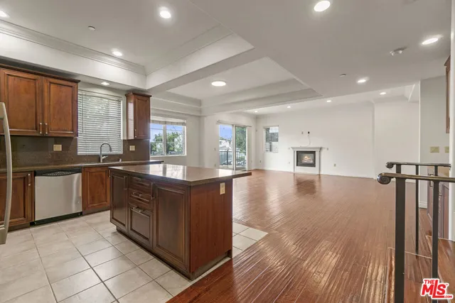 a kitchen with stainless steel appliances granite countertop a stove top oven a sink dishwasher and a refrigerator with wooden floor