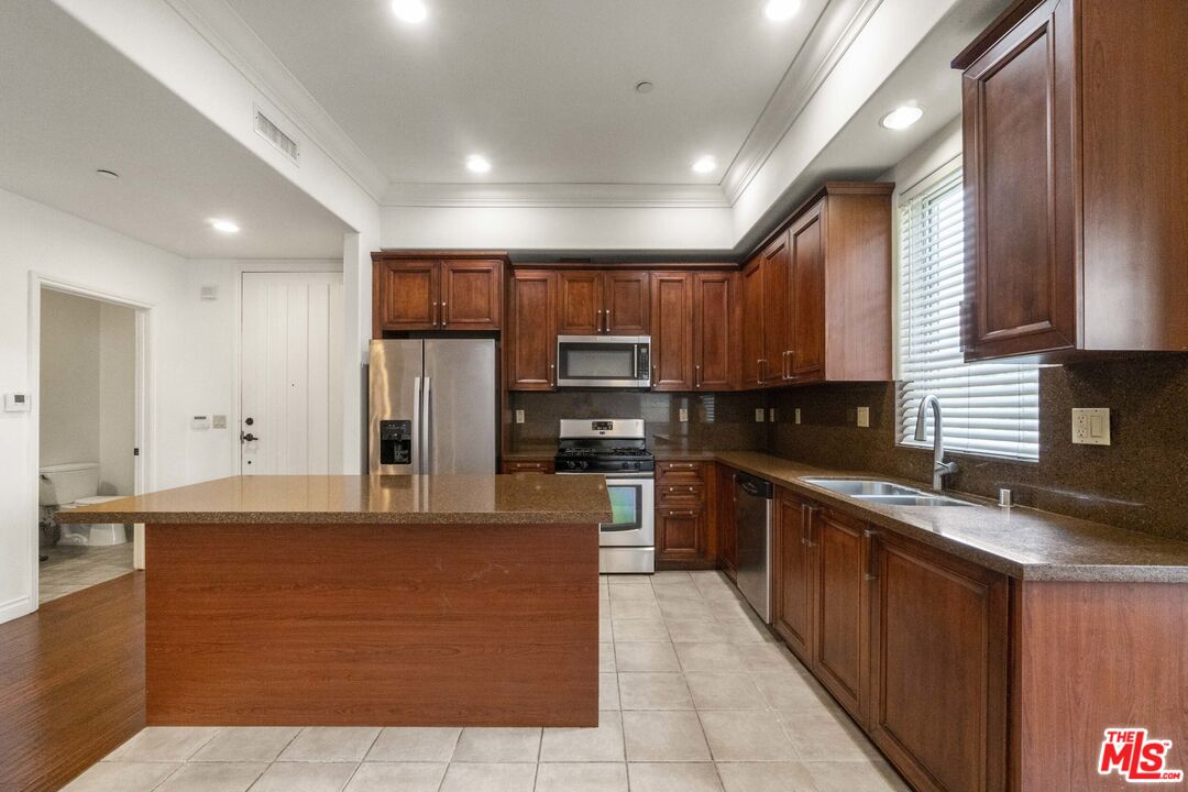 10765 Wilkins Avenue, Unit 8 Los Angeles, CA 90024 - Photo 5 of 33 a large kitchen with stainless steel appliances wooden cabinets a stove a sink and a center island