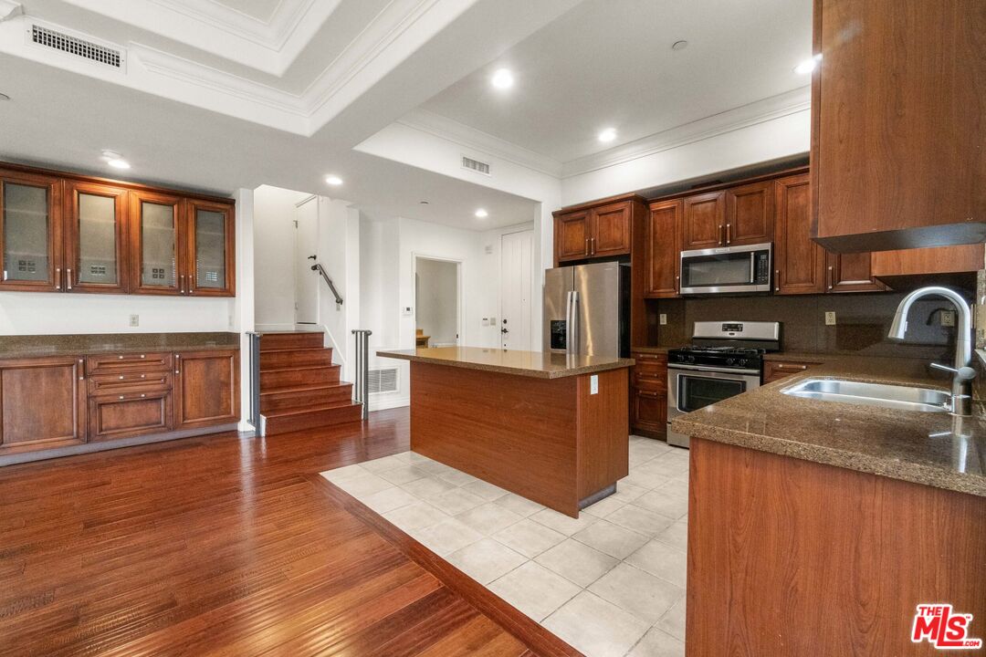 10765 Wilkins Avenue, Unit 8 Los Angeles, CA 90024 - Photo 6 of 33 a kitchen with stainless steel appliances kitchen island granite countertop a stove top oven a sink dishwasher a microwave oven and a refrigerator with wooden floor
