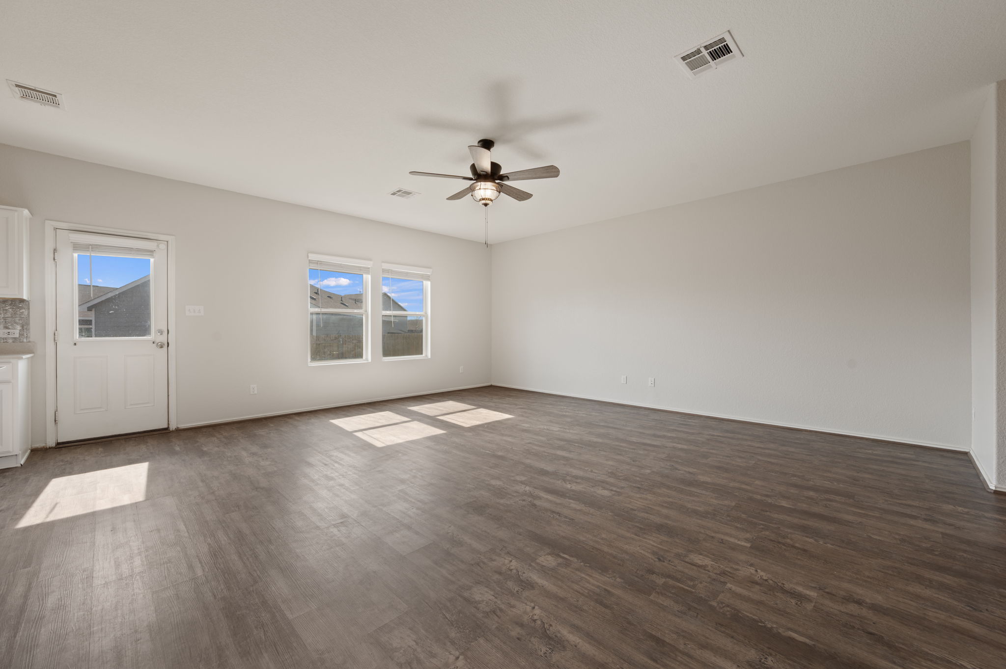 817 Circle Way Jarrell, TX 76537 - Photo 5 of 39 an empty room with wooden floor ceiling fan and windows