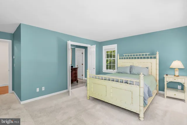 a spacious bedroom with a bed and a lamp