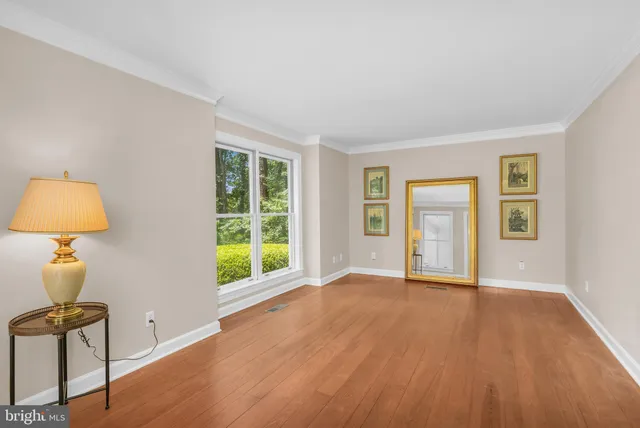 a view of an empty room with window and wooden floor