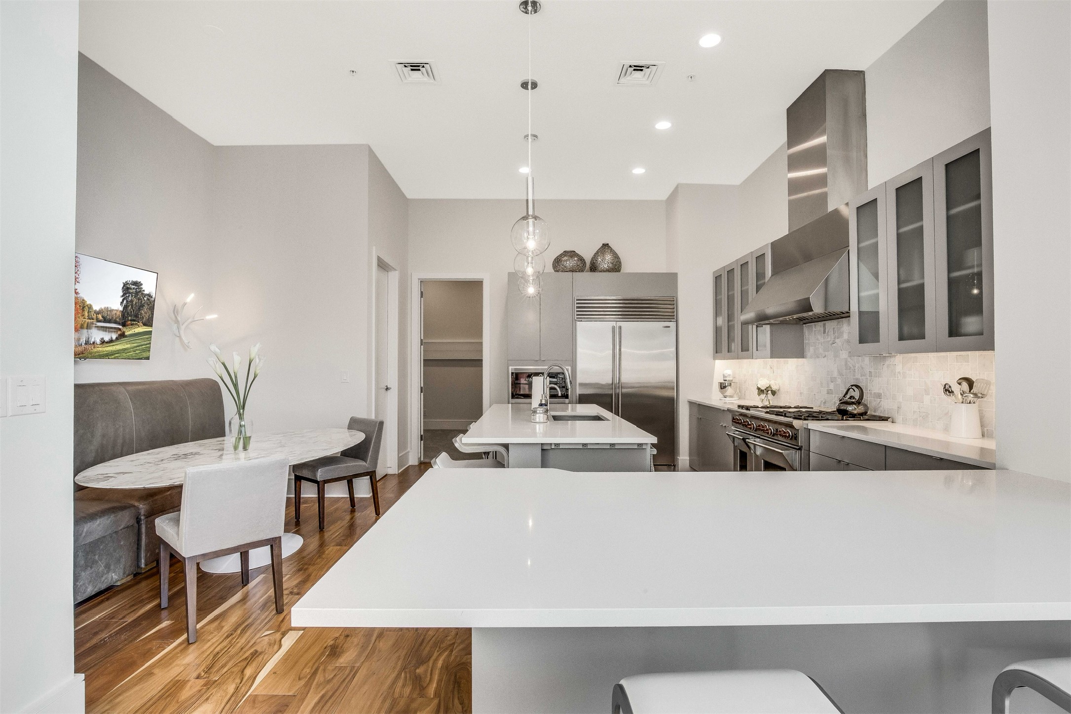 555 East 5th Street, Unit 3022 Austin, TX 78701 - Photo 9 of 40 Kitchen featuring gray cabinets, a breakfast bar, hanging light fixtures, high quality appliances, and an island with sink