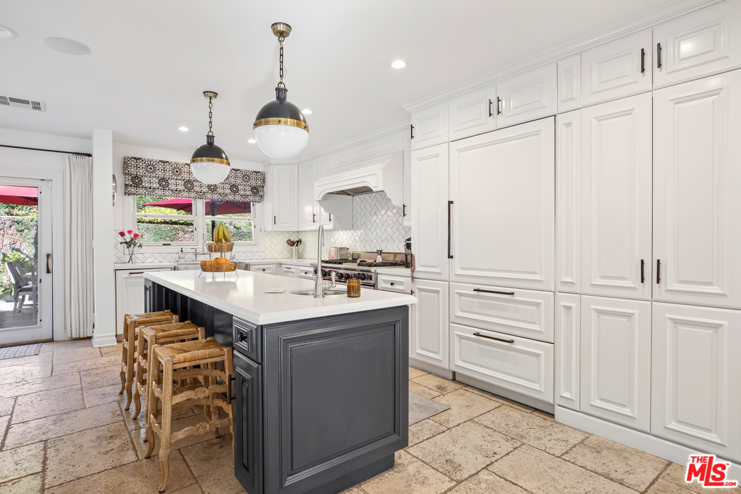 384 Dalkeith Avenue Los Angeles, CA 90049 - Photo 14 of 37 a kitchen with kitchen island granite countertop a sink a counter space and cabinets