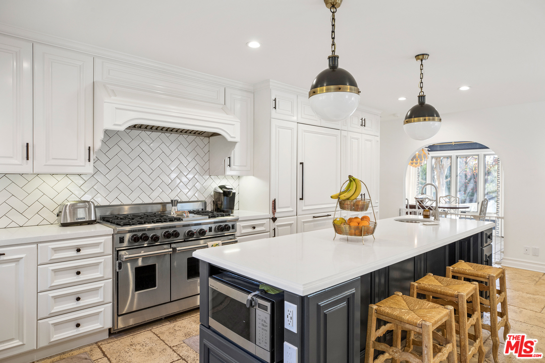 384 Dalkeith Avenue Los Angeles, CA 90049 - Photo 16 of 37 a kitchen with a stove a sink a center island and wooden floor