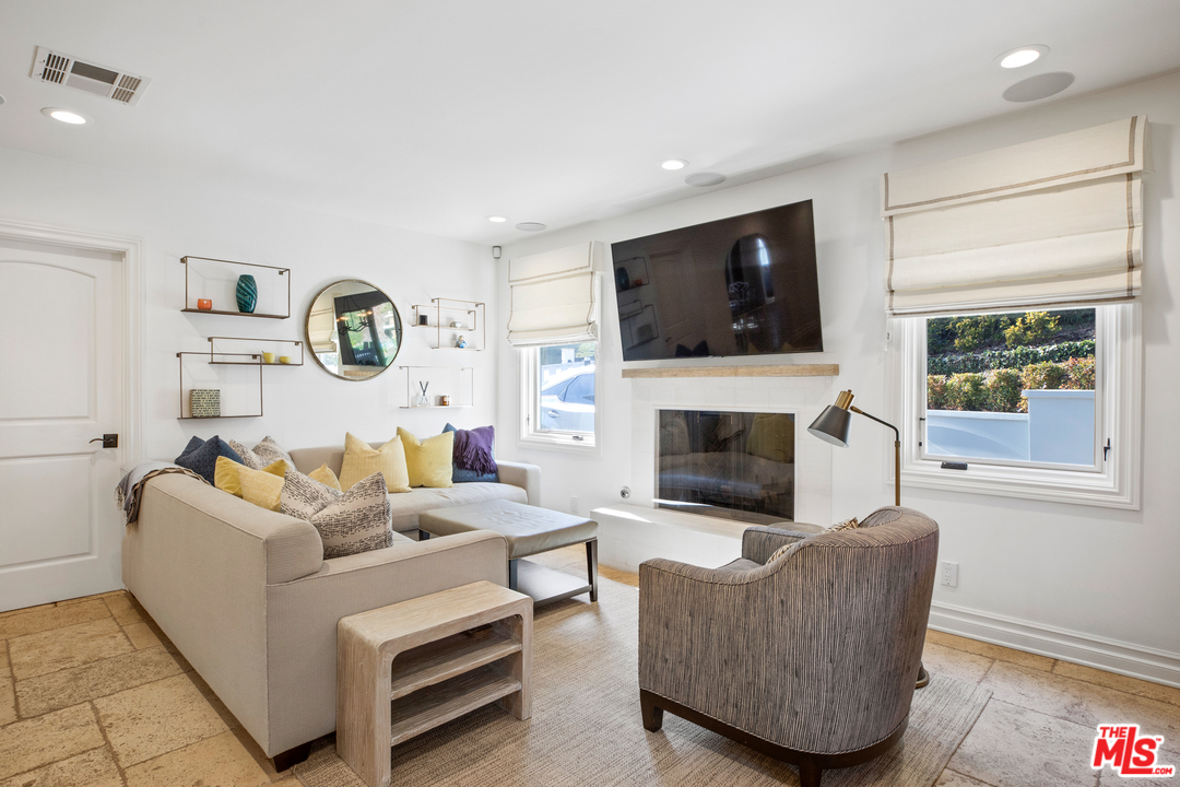 384 Dalkeith Avenue Los Angeles, CA 90049 - Photo 19 of 37 a living room with furniture a flat screen tv and a fireplace