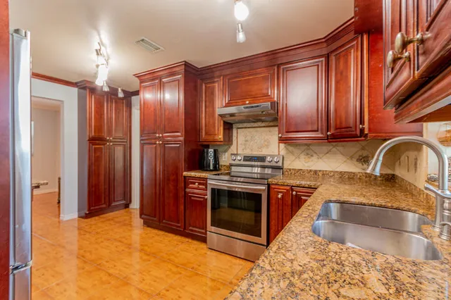 a kitchen with stainless steel appliances granite countertop a stove a sink and a refrigerator