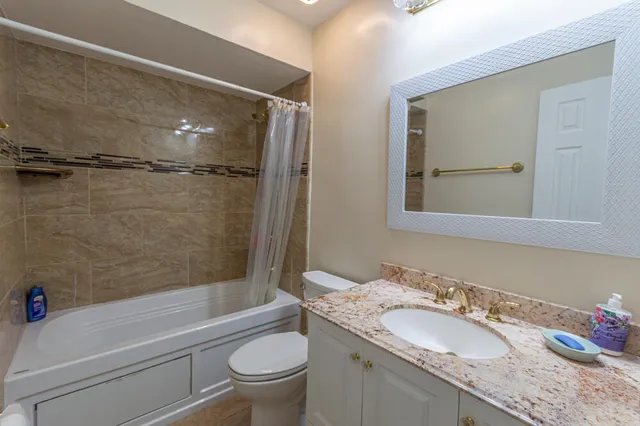 a bathroom with a granite countertop sink toilet mirror and shower