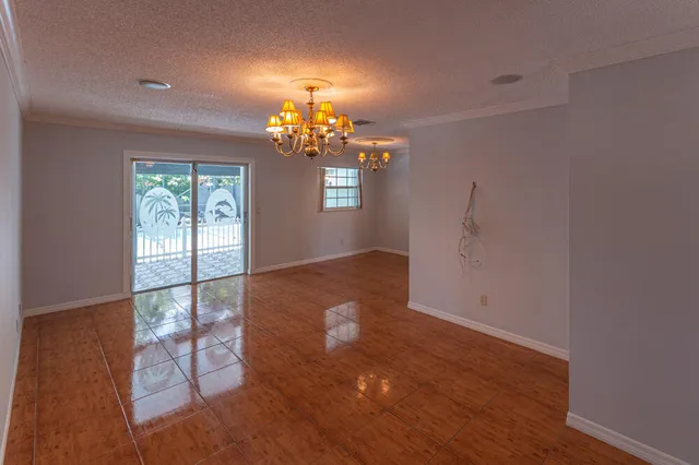 an empty room with wooden floor chandelier and windows