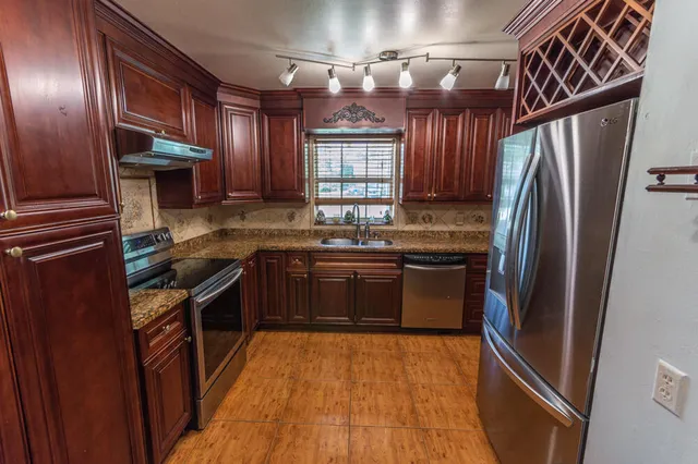 a kitchen with granite countertop stainless steel appliances and wooden cabinets