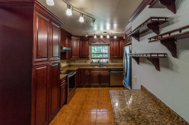 a kitchen with stainless steel appliances granite countertop lots of counter top space and wooden floor