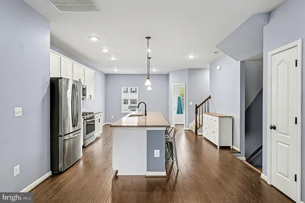 a kitchen with kitchen island a refrigerator a stove a sink and a oven with wooden floor