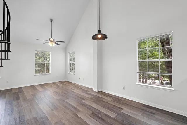 a view of an empty room with a window and wooden floor