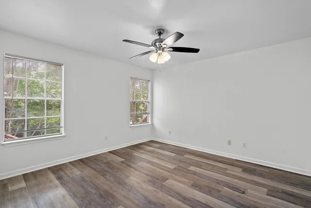 a view of empty room with wooden floor and fan